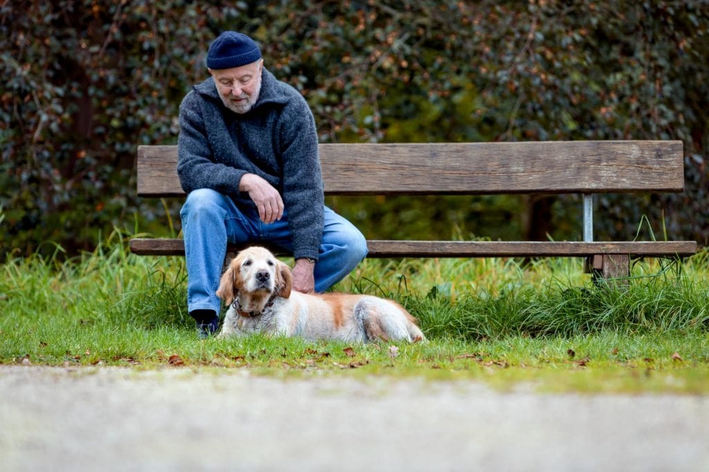 Alter Mann auf Parkbank mit Hund
