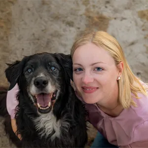 Zufriedene Kundin von Hundefotografin Ines Arnshoff schmiegt sich lachend an ihren alten schwarz-weißen Border Collie – Tierfotografie in Bremen