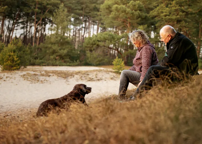 Silke und Thomas sitzen mit ihrer Labrador-Hündin Luna im Dünengras von Sottrum, Fotoshooting mit altem Hund in Niedersachsen.
