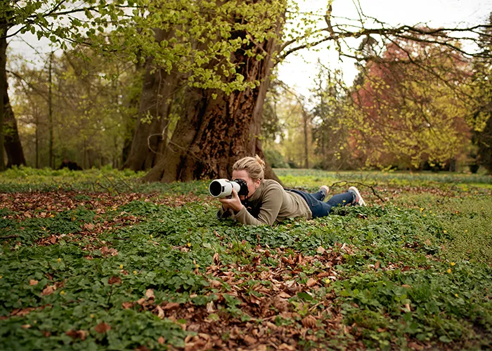 Tierfotografin Ines Arnshoff liegt am Boden und fotografiert mit dem Teleobjektiv auf Augenhöhe des Tieres, Behind the Scenes aus Bremen.