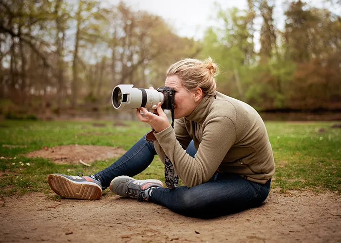 Ines Arnshoff sitzt mit der Kamera am Auge und fotografiert konzentriert während eines Tierfotoshootings, Behind the Scenes einer Tierfotografin in Bremen.