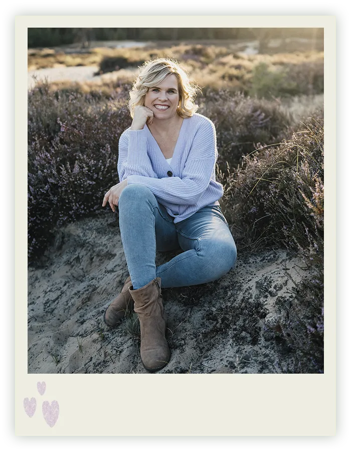Ines Arnshoff sitzt lächelnd in der Abendsonne zwischen blühender Heide