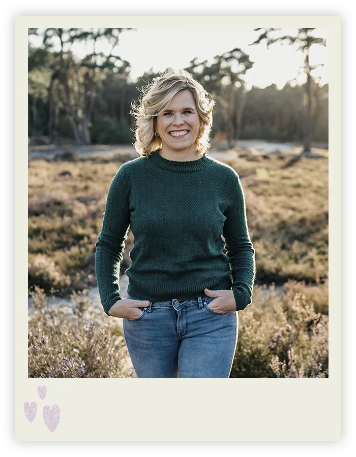 Ines Arnshoff steht lächelnd mit den Händen in den Taschen im Abendlicht der Heidelandschaft